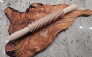 Pici roller on a cutting board of olive wood.